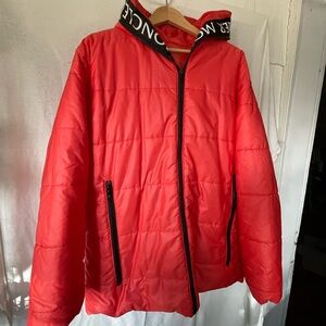 Montcler style orange puffer with name MONTCLER along zipper and hood .